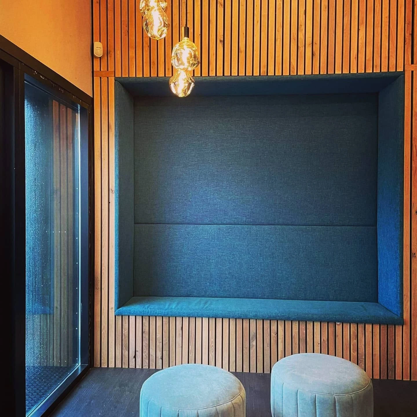 The teal seating alcove against warm timber.